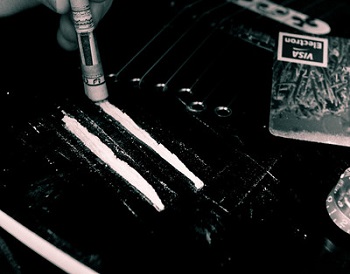 Líneas de cocaína en una mesa con un billete enrollado que se usa para inhalarlas.