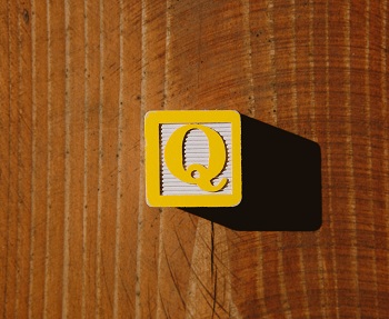 Bloque de letras de un niño amarillo con la letra "Q" en eso.