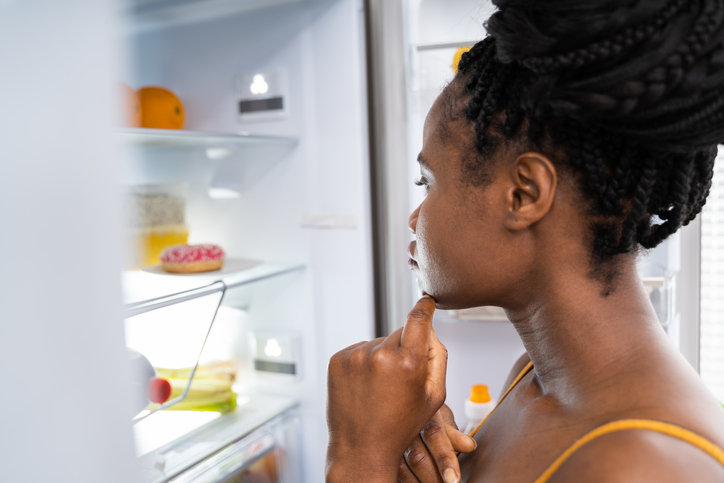 Mujer con hambre después del ejercicio mirando en el frigorífico