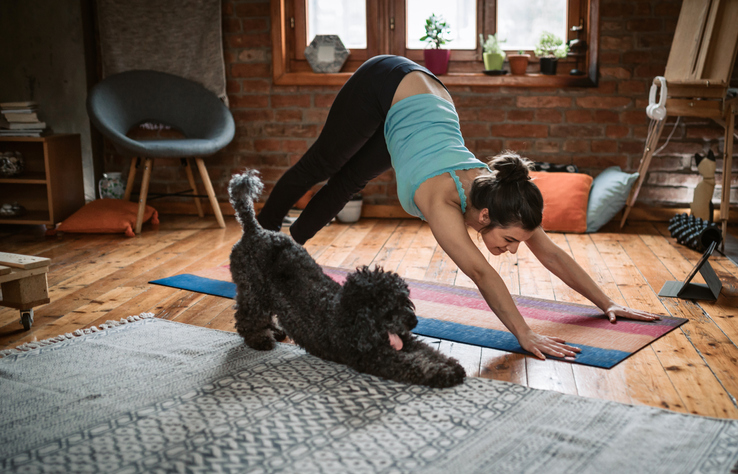mujer haciendo yoga con su perro escuchando su cuerpo